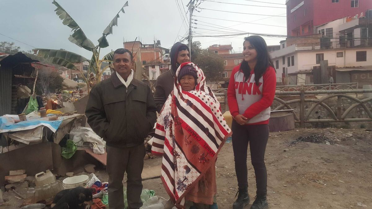 Three visitors stand either side of the woman on the track, one holding the blanket in place.